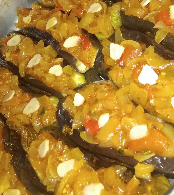 Close-up of stuffed eggplants topped with onion, pepper and garlic
