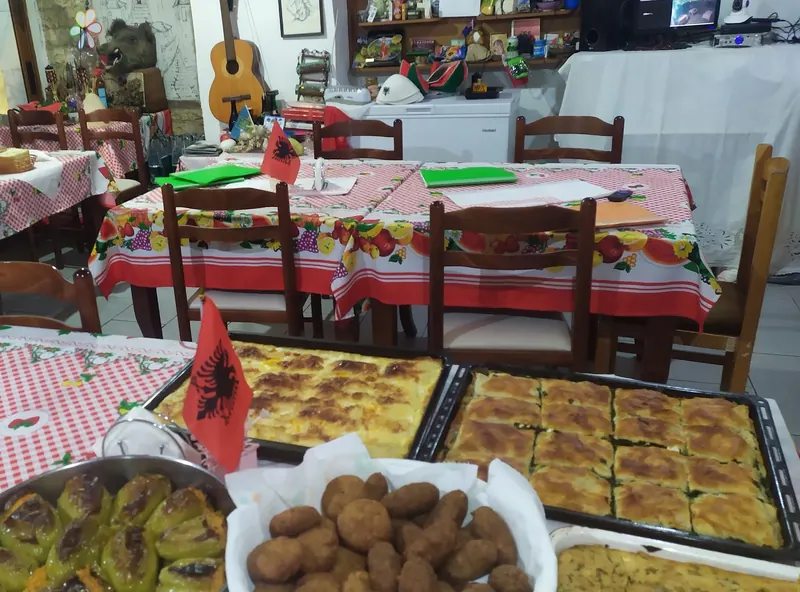 Stuffed peppers, qifqi and trays of pie on a red-checked table, with the dining room behind