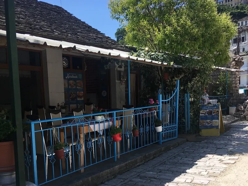 The taverna's terrace with blue railings on a cobbled street in Gjirokastër