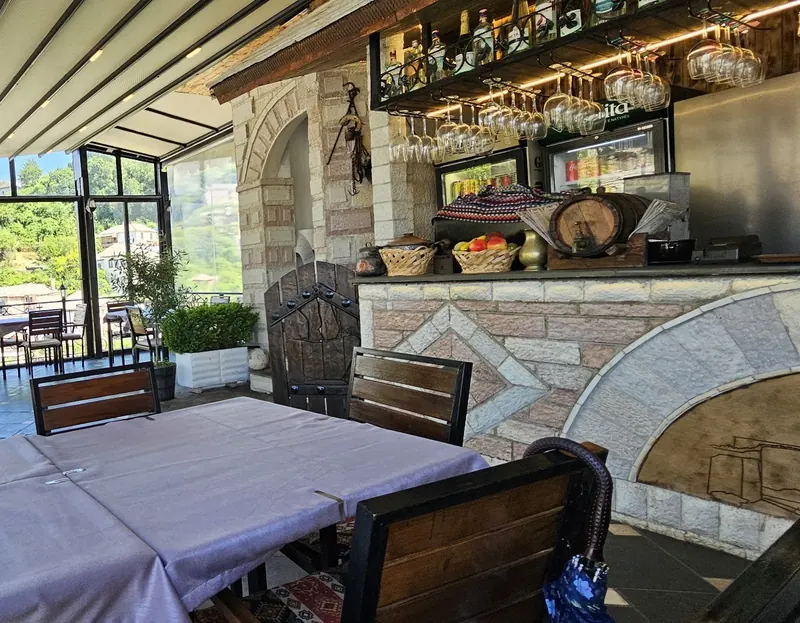 The glass-walled terrace: a stone arch, the bar and green hills through the windows